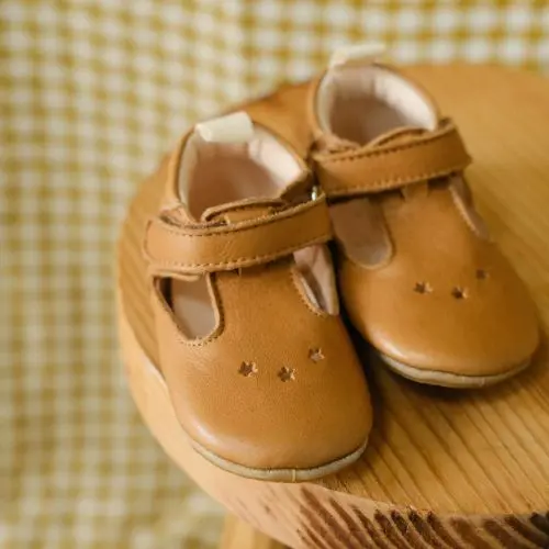 Chaussons césar marron posé sur une chaise avec un fond vichy jaune